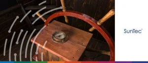 Vintage ship’s wooden steering wheel and compass representing SunTec’s navigation solutions for banks facing economic turbulence.