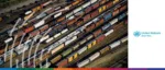 An aerial view of a vast rail yard filled with numerous rows of multi-colored freight cars and tankers. The image is framed by a white sidebar on the right featuring the United Nations UNCITRAL logo. Translucent white, abstract wavy lines are overlaid on the left side of the cargo cars, and a multi-colored gradient bar runs along the very bottom edge.