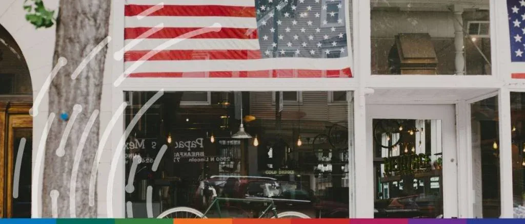 American flags displayed in a storefront window with a bicycle, symbolizing the impact of 2026 US trade policies and strategic minerals initiatives on domestic retail and manufacturing.