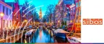 Dusk view of an Amsterdam canal lined with historic townhouses, bicycles, and moored boats featuring the Zuiderkerk tower for Sibos 2022 held in October.