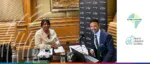 Afreximbank and Trade Finance Global representatives during a recorded interview session featuring a laptop, microphone, and branded backdrop.