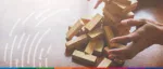A Jenga tower of wooden blocks falling, symbolizing the high risk of global trade collapse and financial instability in 2026.
